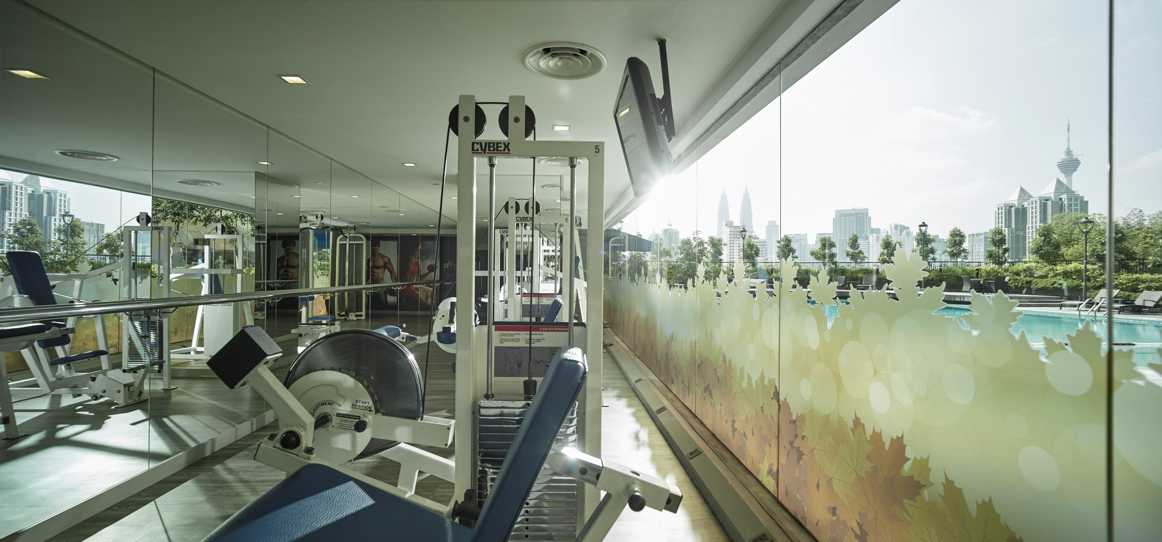 Sunway Putra Hotel Kuala Lumpur Exterior photo The photo shows a gym or fitness area. In the foreground, there are various pieces of gym equipment, including a weight machine and a rowing machine. The space is well-lit and features large windows that provide a view of the outside, where you can s