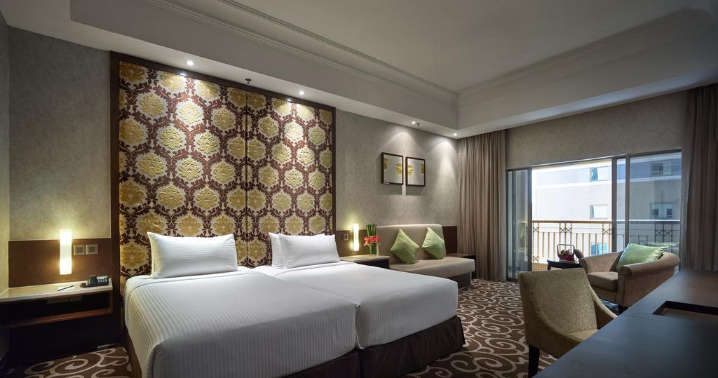 Sunway Putra Hotel Kuala Lumpur Exterior photo The photo shows a modern hotel room featuring two twin beds with white bedding. The wall behind the beds has a decorative patterned design in warm colors. There are two framed pictures above the beds. A small seating area is visible, which includes a