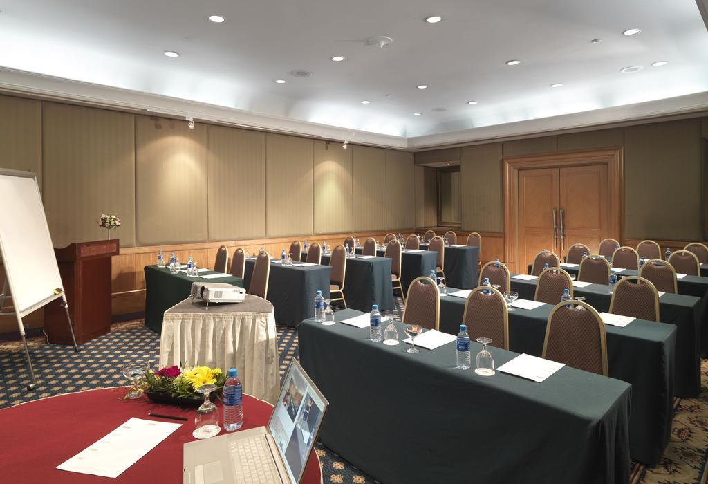 Sunway Putra Hotel Kuala Lumpur Exterior photo The photo shows a meeting or conference room set up for a presentation or workshop. It features several rows of chairs arranged in front of tables covered with green cloths. Each table has a notepad and a bottle of water placed on it. There is a proj